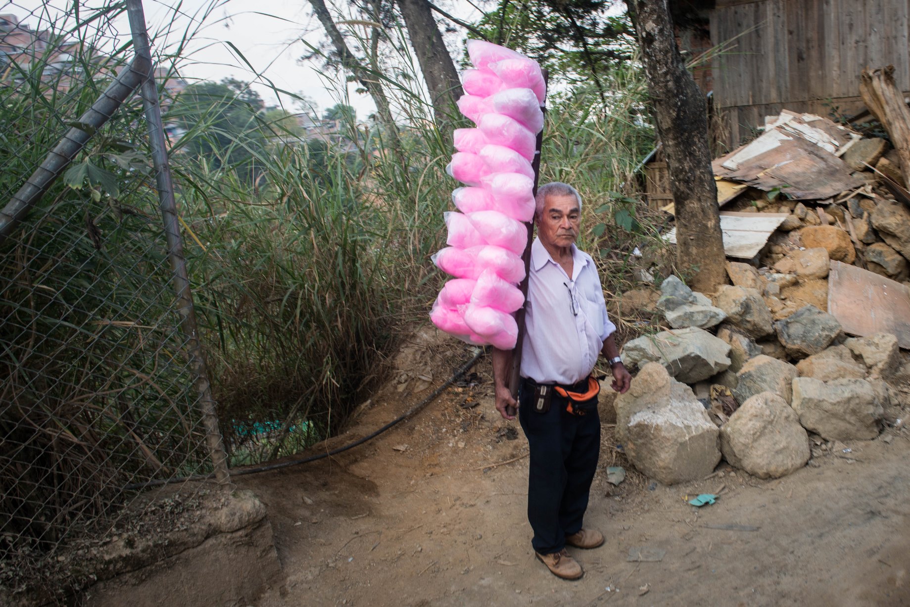 En la fotografía, un hombre vende algodón de azúcar al costado del camino. El desempleo es un grave obstáculo para el desarrollo y bienestar de la comunidad. La economía local de Granizal aún está en pañales. Los mercados laborales en Bello y Medellín en su mayoría siguen siendo inaccesibles debido al elevado costo del transporte y el acceso limitado a la capacitación educativa y vocacional. El nivel de educación más alto alcanzado por casi la mitad de la población de Altos de Oriente es la escuela primaria y sólo el 29% de la población alcanza la educación secundaria. Sólo un tercio de la población activa de la comunidad participa en actividades generadoras de ingresos, y la mayoría son informales. Gracias al apoyo de la Universidad de Antioquia, muchos miembros de la comunidad ahora están teniendo acceso a cursos y programas educativos. La generación más joven de miembros de la comunidad, sin embargo, se esfuerza para romper estas barreras económicas. La disponibilidad de escuelas y la paz relativa les han permitido a los nacidos y criados en Altos de Oriente tener acceso regular a la escolarización. Algunos jóvenes, muy pocos,  son los primeros de sus familias en alcanzar la educación terciaria.